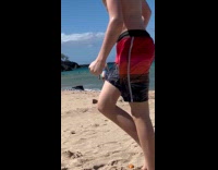 Woman bikini faces ocean phone behind her