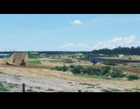 Motorbikes jump off big ramp and ride on bumps on dirt race track