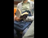 Man holding book watches musician play saxophone 