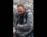 Collab DailyDoseOfInternet - Pet owner carries black dog in jacket while it rains 