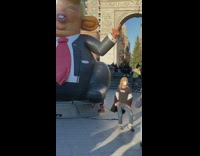Blonde guy beside large trump balloon arch