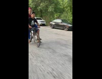 Two guys ride one bike bicycle, one guy sits on top tube frame
