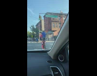 Guy rides tall bicycle pink dragon doll 