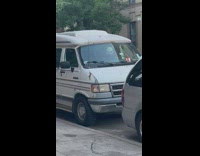 Van parked on the street with a white mask hanging on the mirror 
