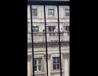 Shirtless man laying down on balcony ledge