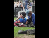 Old man lays on grass at the park and kisses wifes feet