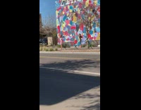 A girl takes pictures in front colorful mural