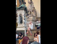 Woman white dress selfie video beside statue