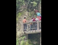 Man shirtless poses on the bridge next to the tourist around him