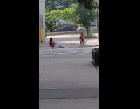 Red shirt girl sits ground by crosswalk 