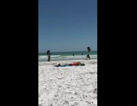 Guy photographs two girls on beach camera 