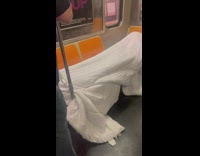 Person wrapped up in a blanket sleeping on multiple seats