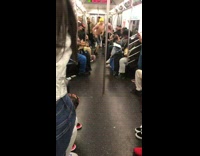 Man in yellow bandana dances on subway poles to hop hop music on train