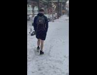 Guy walking in snowstorm with basketball shorts