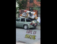 Gray suv car packed with furniture in truck and on roof