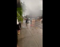 Man clears flooded street sewer while raining