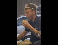 A guy at a desk with crown eating cake
