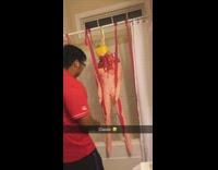 Man in red polo touches and slaps a tied up blow up doll