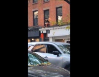 Lady toss candies from window for Halloween