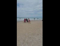 Three people fur robes walk together beach 