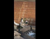 Woman white pants beside wall water gardens