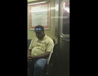 Man wears marquee hat that says Insane in the membrane on subway train