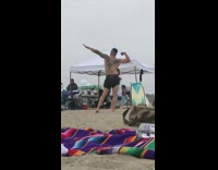 Guy flexes muscles for picture at beach