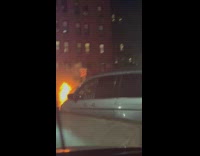 Car in flames along the road at night in NYC 
