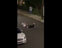 Two men lie down in the middle of the street