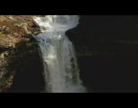 Guy kayaks down rapids and falls down waterfall green boat