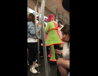Woman wears neon green pink net mesh dress and pants with net mask on subway train