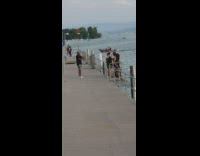 Dad photographs mom two daughters railing lake 