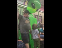 A small kid with giant green inflatable alient