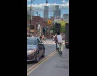 Guy bikes with trashcan on head white shirt 