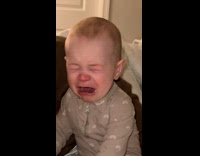 Baby in bed with mom  looks at dad and cries 