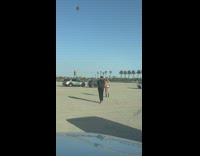 Woman in shiny dress poses while cars pass by behind