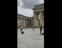 Blonde woman gate with statues cameraman on ground