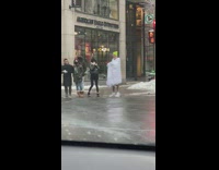 Guy covered by white mattress street snow