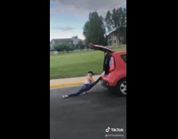 Woman does splits on trunk of car