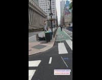 Man in gray white striped dress stands on trash can and plays the flute