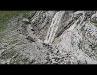 Woman bikini photo shoot under rocky waterfalls 