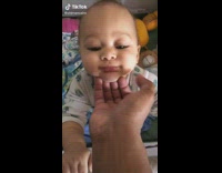 Dad puts hand under babys chin and jiggles face 