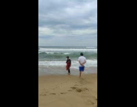 Family at the beach and the parents enjoys the waves
