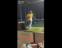 Woman swings golf club with one arm 