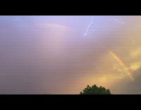 Lightning under the rainbow arc at sunset