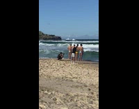Four men in speedos touch each other beach