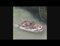 2 guys ride on raft being pushed by leaf blower 