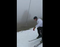 Skier rides on grass then backflips on small snow ramps