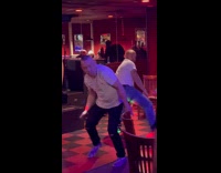 Two men twerk back to back with each other