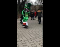 Two men dressed in leprechaun costumes ride hoverboards and play music in park 